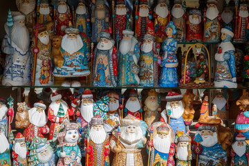 Many Russian colorful dolls - Santa Clauses, snow maidens, snowmens stand on the shelf in the store in anticipation of foreign tourists