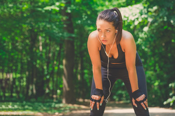 Portrait of woman resting with hands on knees in the park.
