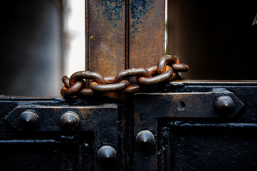 old metal gates are covered with a rusty metal chain.