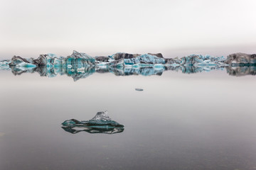 Bluish drift ice separates sky and water on a covered day © Lux
