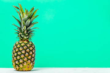 Fresh pineapple isolated on green background. Tropical fruit on table.