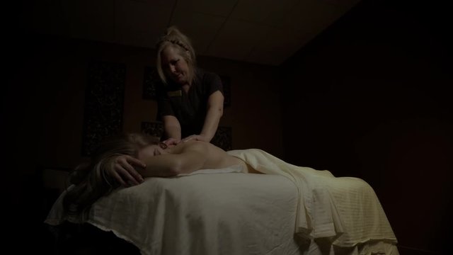 Young female getting a back and head massage with hands and hot stones
