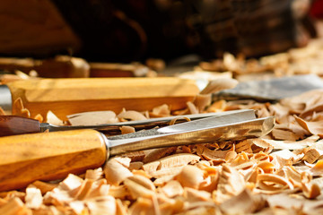 Chisels laid in wooden shavings on the desk. Carving tools lying in the shavings. In a carving...