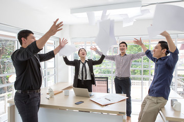 Group of happy business people cheering in office.