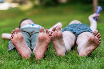 Children lie on the grass, dirty feet on foreground