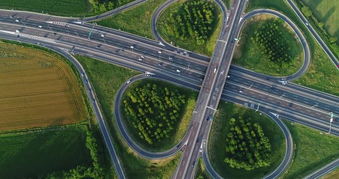 Cloverleaf interchange seen from above. Aerial view of highway road junction in the countryside with trees and cultivated fields. Bird's eye view.