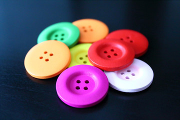 Beautiful colored wooden buttons on a black background. Close-up. Background. Isolated.