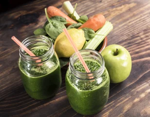 Crédence de cuisine en verre imprimé Jus Épinards au jus de pomme et de légumes un pot de boisson gazeuse avec de la paille sur une table en bois