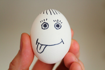 Chicken egg with a painted face in a man's hand. Close-up.