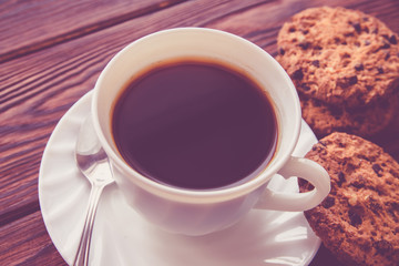 A cup of hot coffee stands on a wooden table 