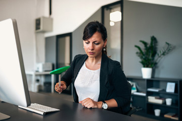 Annoyed businesswoman hitting a fly with flyswatter.