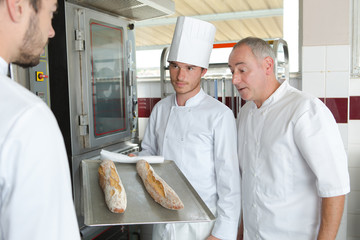 apprentice baker in bakehouse with tray of bread
