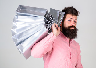 Shopping concept. Guy shopping on sales season, carries bunch of bags on shoulder. Man with beard...