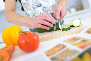 cutting cucumber on cutting board in kitchen at restaurant