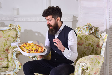 Man with beard and mustache holds delivered box with tasty fresh hot pizza. Pizza delivery concept....