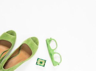 Beauty blog concept. Woman outfit. Green heels, green sunglasses, green vintage brooch on white...