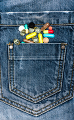 Medicine chest concept. Pocket with colorful pills as symbol of diversity of medicine chest. Pills or medicine tablets scattered on jeans, denim background