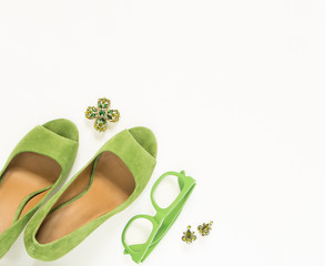 Beauty blog concept. Woman outfit. Green heels, green sunglasses, green vintage brooch on white...
