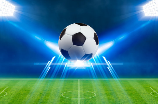 Soccer ball, bright spotlights, illuminates green soccer stadium