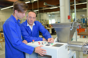 Man explaining controls of machine to junior worker