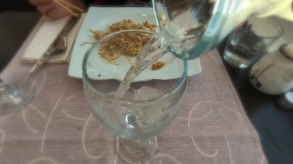 SLOW MOTION: Close up of pouring sparkling white wine into a glass at dinner in a restaurant with romantic blur effect and slow motion. - Powered by Adobe