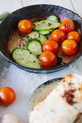 Fresh and ripe vegetables - tomatoes and cucumbers, roasted on fry pan.
