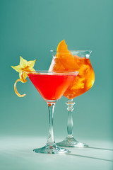 Two exotic cocktails of red color in glasses with ice.