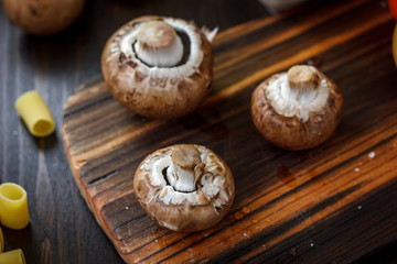 Obraz na płótnie Canvas Raw mushrooms on wooden board. Three mushrooms on kitchen.