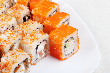 Fresh appetizing rolls on a white plate. A bright photo of Japanese food. Close-up of a selective focus.