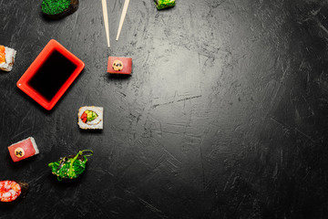 Top view of Japanese Sushi and chopsticks on black background. Sushi rolls, nigiri, maki, pickled ginger, wasabi, soy sauce. Space for text. Top view. Sushi background. food frame