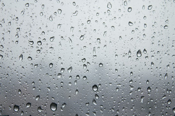 Depression and dreary sad weather shown as water droplets on a window.