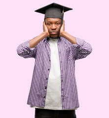 Young african graduate student black man covering ears ignoring annoying loud noise, plugs ears to...