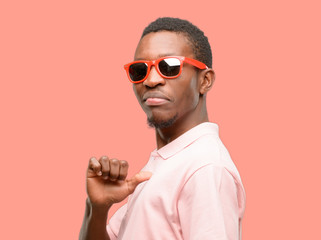African black man wearing sunglasses proud, excited and arrogant, pointing with victory face