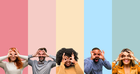Cool group of people, woman and man looking at camera through fingers in ok gesture. Imitating...