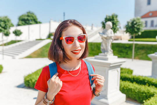 Happy young woman tourist walking and admiring view of a typical but wonderful flower garden in baroque style in Europe at sunny summer day. Travel destinations concept