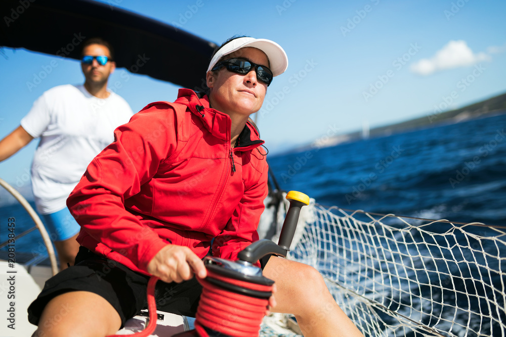 Wall mural Attractive strong woman sailing with her boat