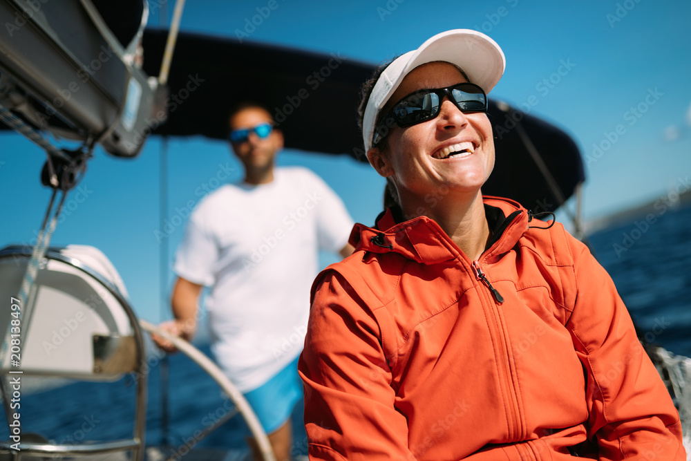 Wall mural Attractive strong woman sailing with her boat