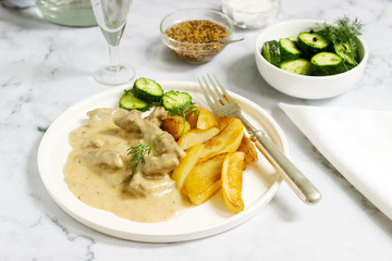 Beef Stroganoff traditional Russian dish of beef in sauce, served with fried potatoes, canned cucumbers, vodka.