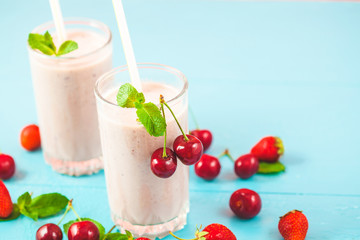 two glasses of smoothies made from milk, strawberries, banana, cherries, decorated with mint on bright pink blue background Concept healthy lifestyle, diet, tasty Copy space