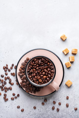 Cup with coffee beans inside on gray concrete background. Top view.
