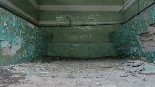 Interior of old room cracked ceramic tiles falling off from the wall in old factory, workshop, shop
