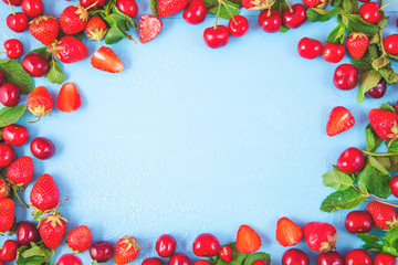 Naklejka na ściany i meble Berries of strawberries and cherries and mint on a blue background. Concept banners and postcards Copy space Top view