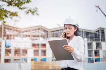 Female engineer inspecting construction work in hand holding clipboard with document.
