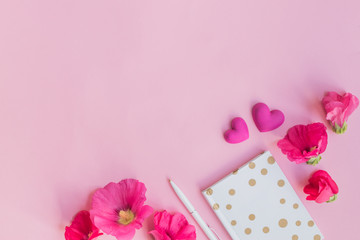 Flat lay desk with pink flowers and notebook