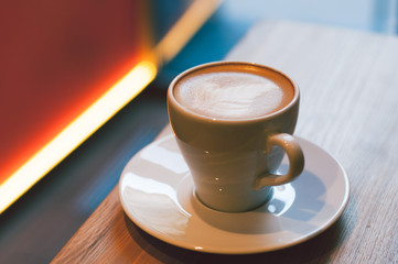 Cup of cappuccino in cafe atmosphere. Hipster / Vintage tone. Closeup, selective focus, blur background.