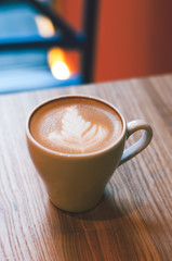 Late arts coffe. White cup of hot coffee on wooden table.