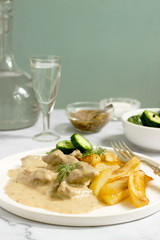 Beef Stroganoff traditional Russian dish of beef in sauce, served with fried potatoes, canned cucumbers, vodka.