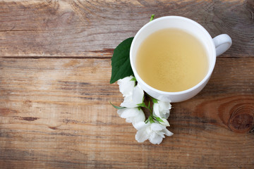 Glass cup of tea with jasmine flowers on wooden background. Top view