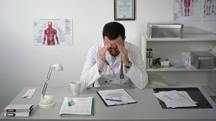 Tired doctor at medical cabinet