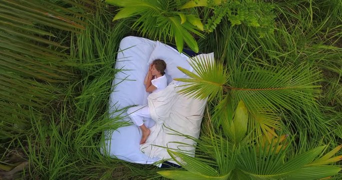 A hidden place. Sleeping woman in deep jungle forest lies on airbed